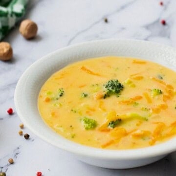 Bowl of Broccoli Cheddar soup in white bowl with nutmeg in background.