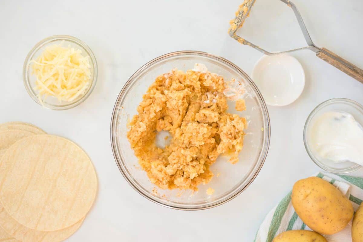 Mashed Yukon gold potatoes in mixing bowl seasoned with taco seasoning and sour cream.