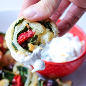 Greek pinwheel recipe being dipped into Tzatziki sauce.