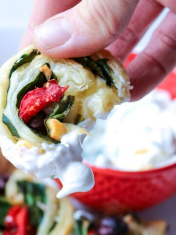 Greek pinwheel recipe being dipped into Tzatziki sauce.