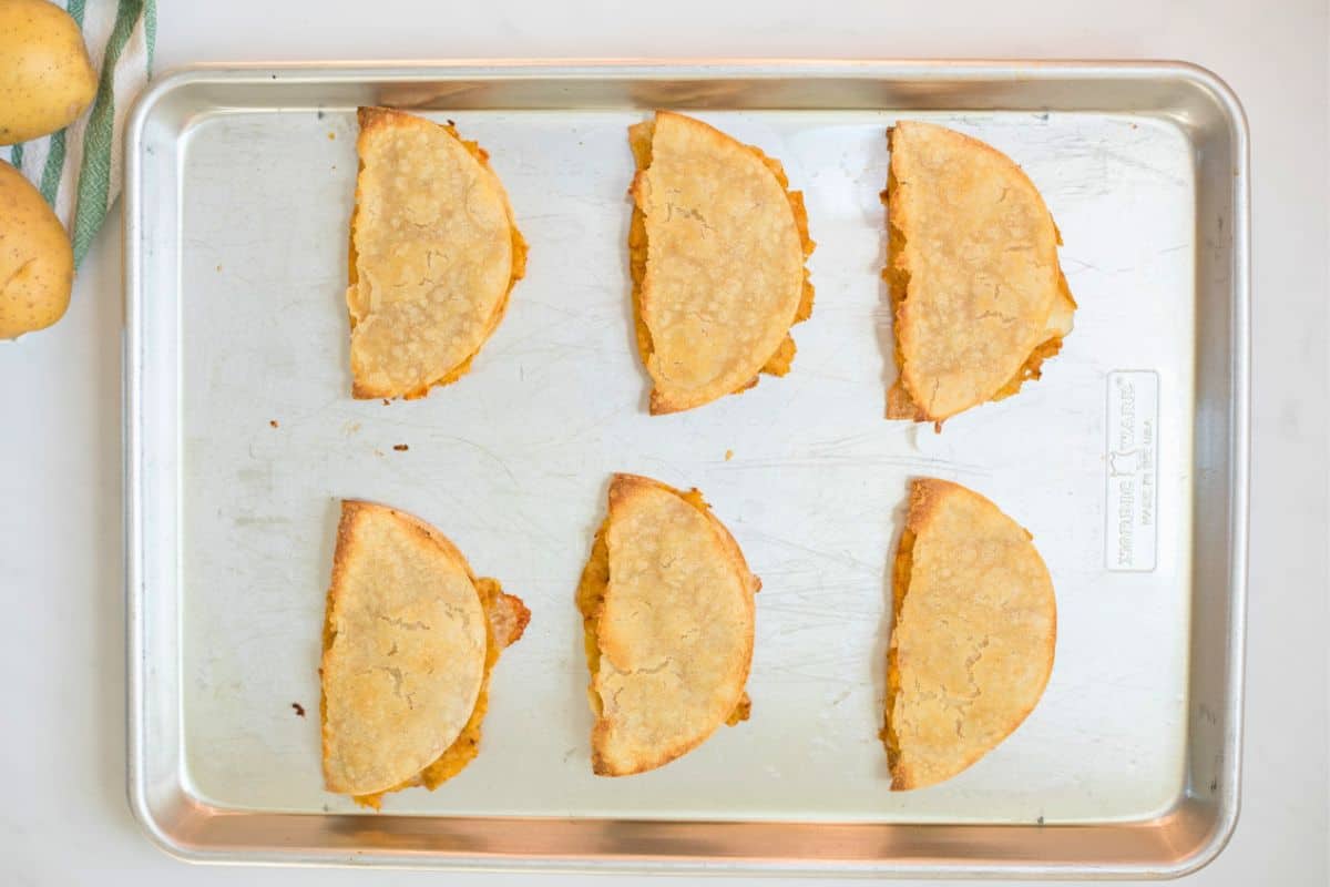 6 potato tacos on baking sheet after being baked.