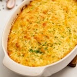 Baked Cheesy Potatoes Romanoff in casserole topped with minced chives.