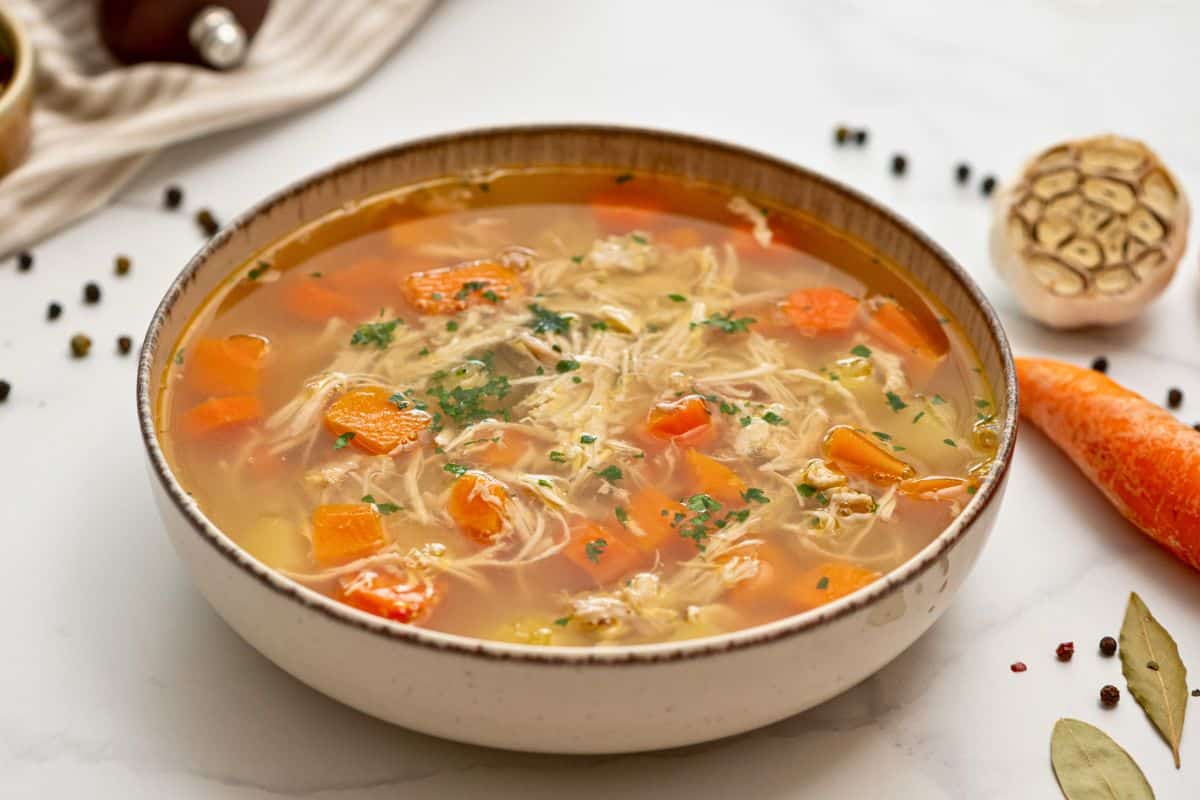 Comforting Soups Bowl of homemade chicken soup filled with shredded chicken and tender potatoes and carrots.