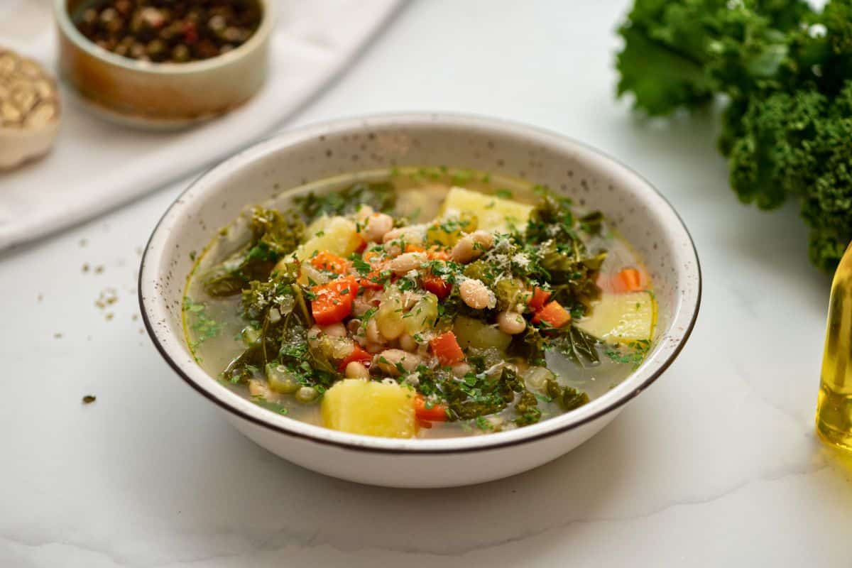 Warming Soup Recipes Bowl of homemade white bean soup with kale topped with parmesan cheese.