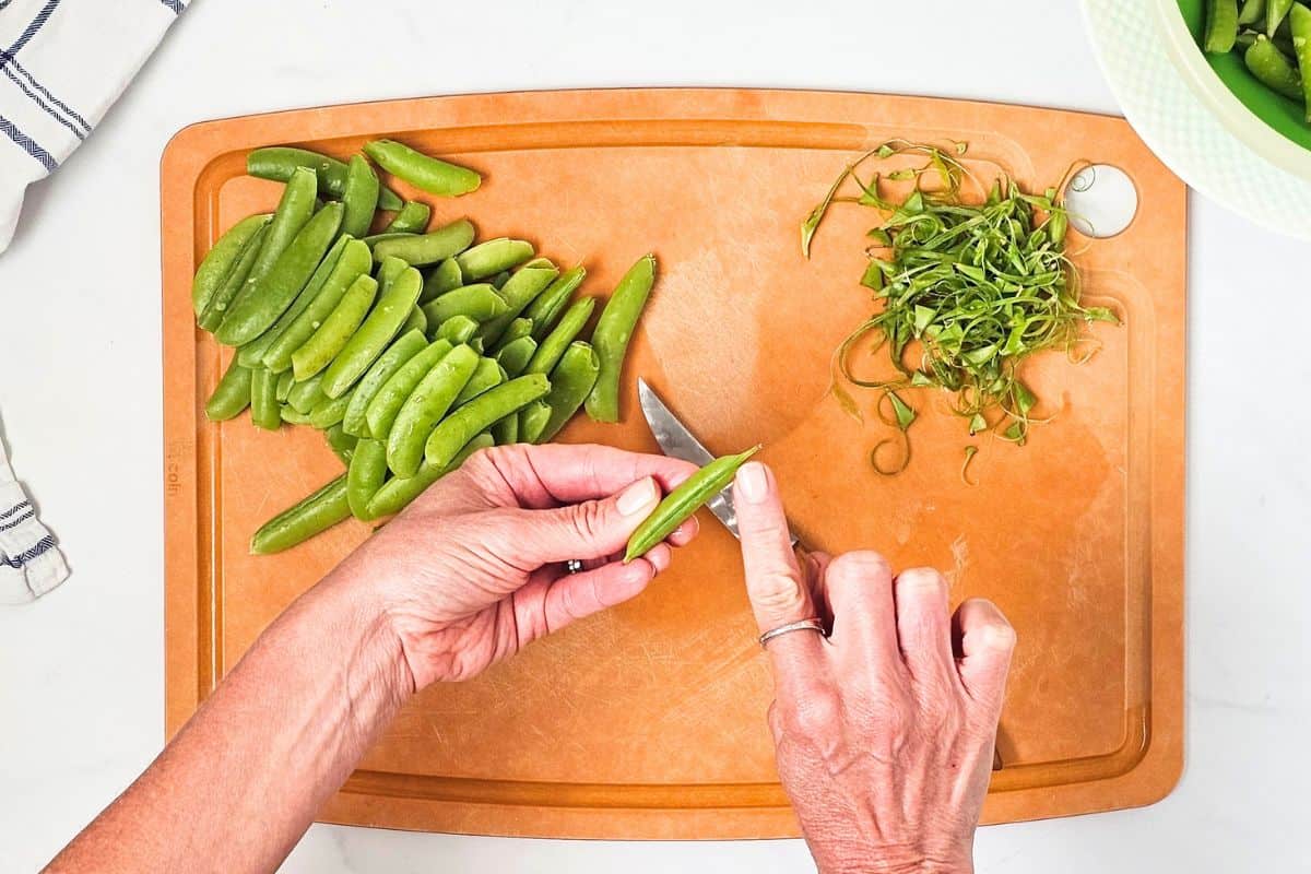 Sugar Snap Pea Recipe Finger pointing to stem end on sugar snap pea to show where to trim.