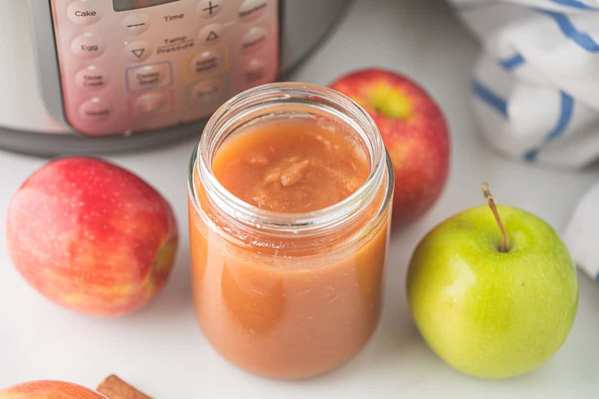 Thanksgiving Recipes Instant Pot Jar of homemade no-peel, naturally sweetened applesauce next to Golden delicious and gala apples.