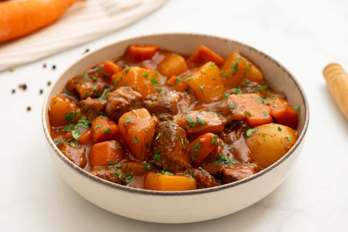 Slow Cooker Beef Stew Recipe Bowl of crockpot beef stew with potatoes, carrots, and glistening thick broth topped with parsley.