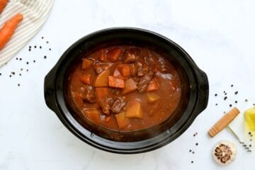 Beef Stew with potatoes and carrots in slow cooker after slow cooking but before being thickened.