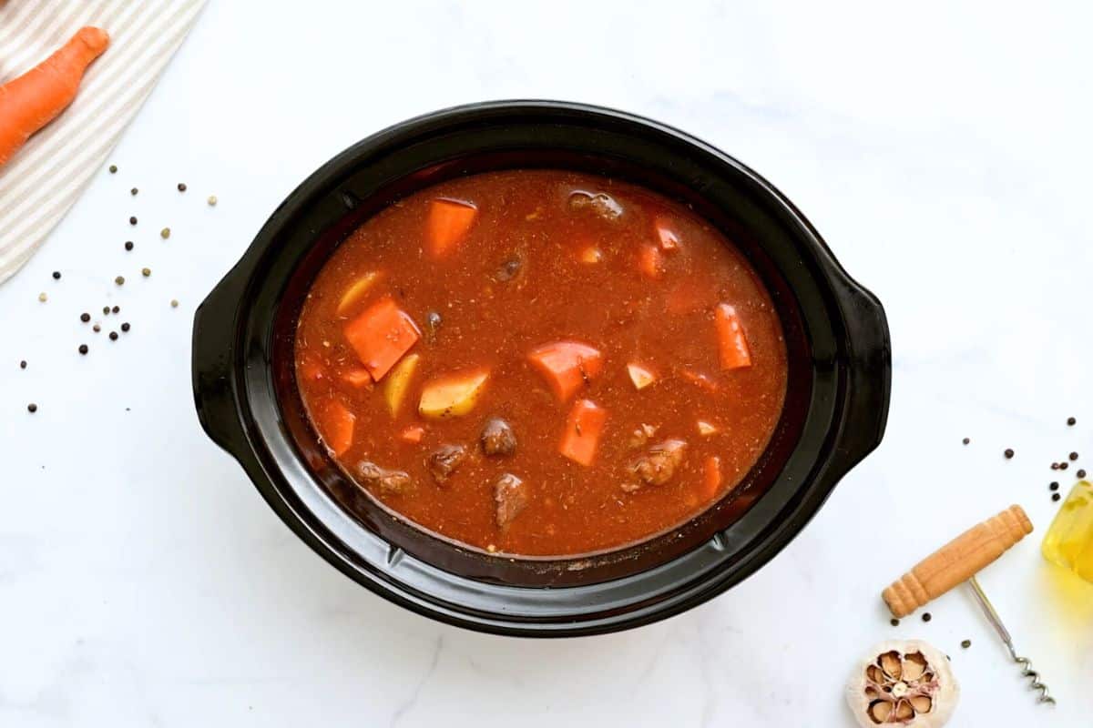 Beef Stew Slow Cooker Browned beef, beef stock, tomato paste, potatoes and carrots in slow cooker before slow cooking.