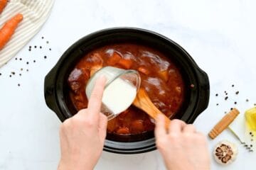 Cornstarch slurry being whisked into slow cooked beef stew.