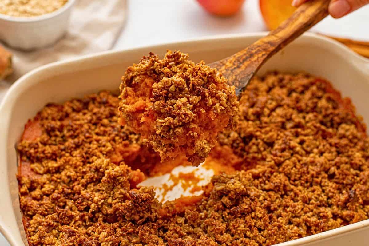 Freezer Friendly Thanksgiving Dishes Spoonful of dairy-free and gluten-free sweet potato casserole coming out of baking dish.