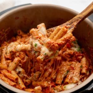 Wooden spoon scooping out cheesy ziti from inside Instant Pot.