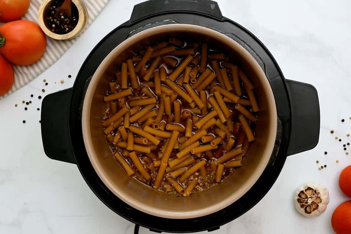 Stock, wine, seasonings and ziti noodles layered inside Instant Pot.