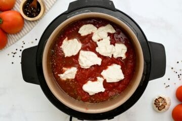 Stock, wine, seasonings and ziti noodles layered inside Instant Pot topped with tomato sauce and dollops of ricotta cheese.