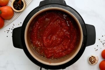 Stock, wine, seasonings, ziti noodles layered inside Instant Pot topped with diced tomatoes and spaghetti sauce.