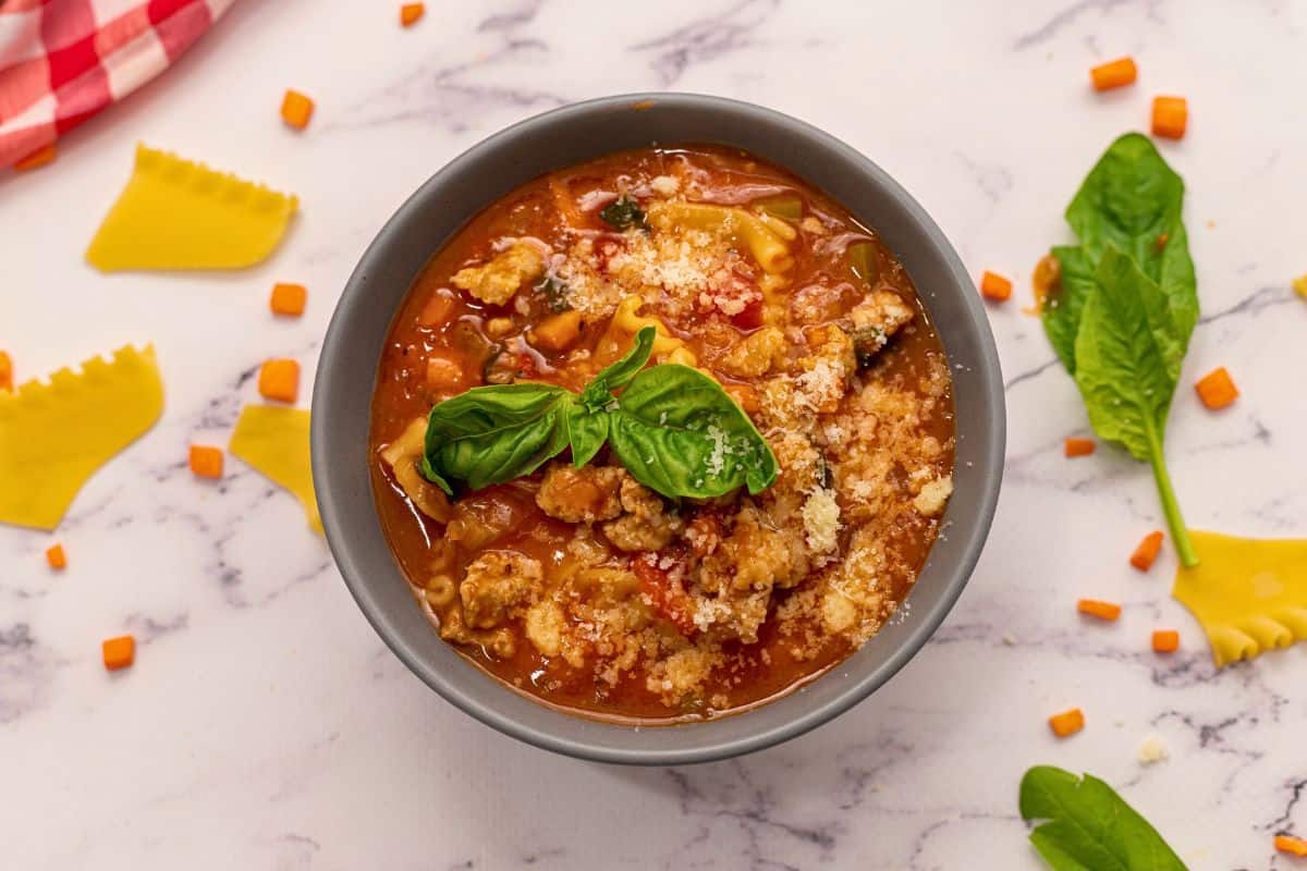 Soups Recipes for Stove Bowl of Lasagna soup made with Italian Sausage and Lasagna noodles topped with cheese and basil.