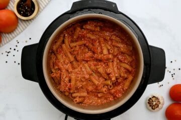 Ziti cooked with tomato sauce and ricotta stirred together inside inner pot of electric pressure cooker.