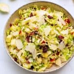 Salad dished out made with shaved Brussels Sprouts tossed with honey lemon dressing, diced apples, dried cranberries, shaved parmesan, and chopped toasted pecans.