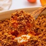 Spoonful of vegan sweet potato casserole topped with Gluten-Free Streusel coming out of baking dish.