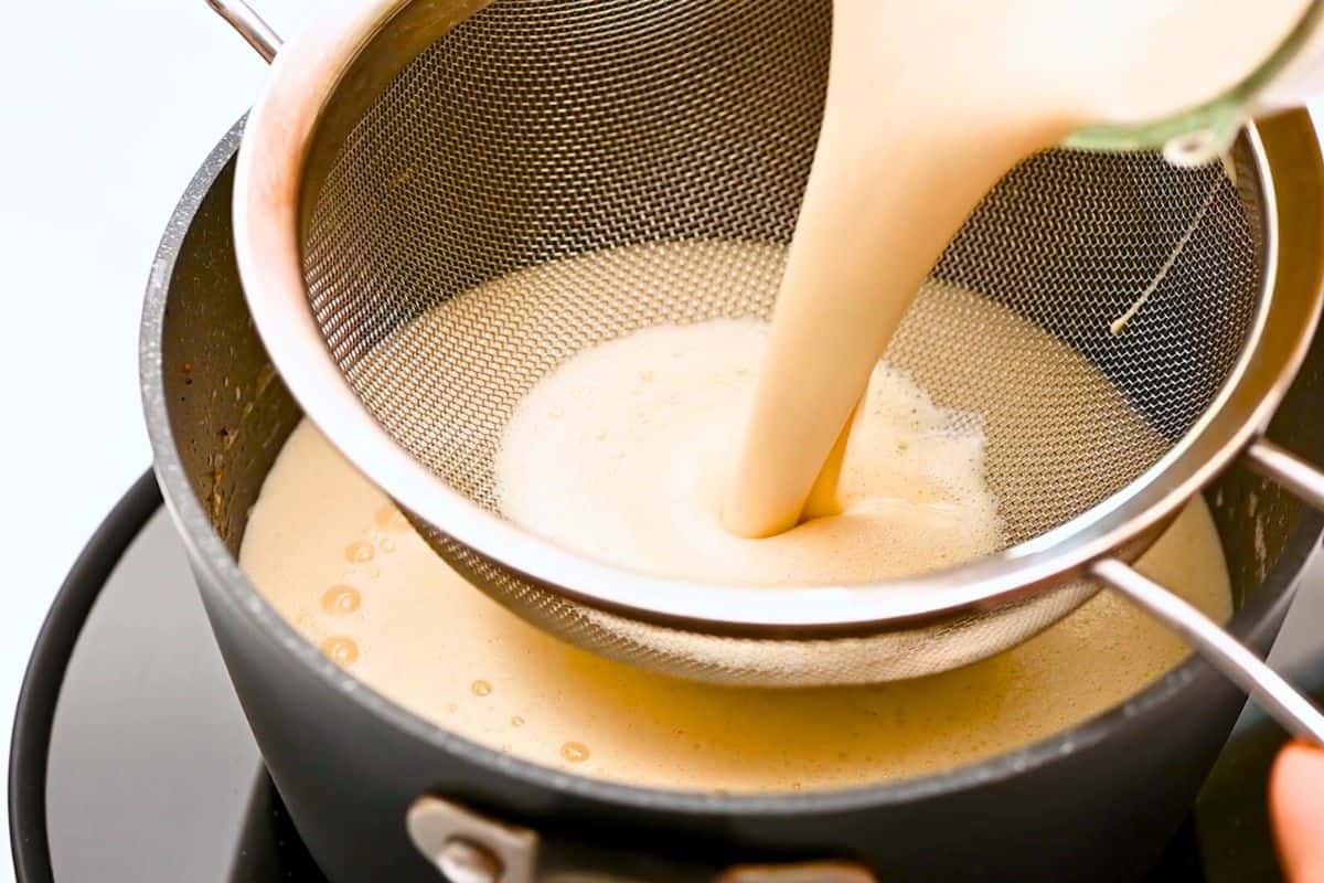 Eggnog Dairy-Free Blended eggnog being poured through fine mesh strainer to remove any lumps.