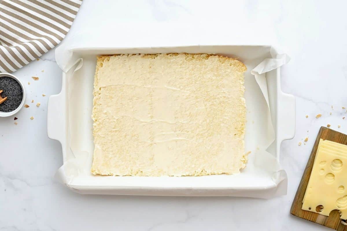 Ham and Cheese Hawaiian Sliders Split bottom half of Hawaiian rolls covered with thin layer of mayo in baking dish lined with parchment paper.