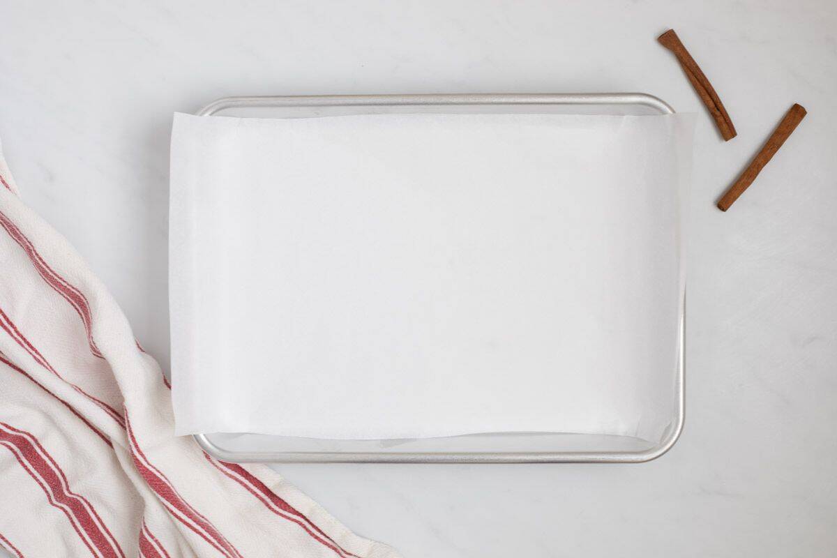 Parchment paper lined on rimmed baking sheet for candied walnuts.