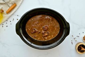 Seared beef, reduced wine, seasonings and beef stock layered in crock pot before slow cooking.