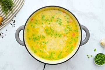 Broth simmered with chicken stock, shredded chicken, peas, carrots, and potatoes to form creamy chicken and dumpling soup.