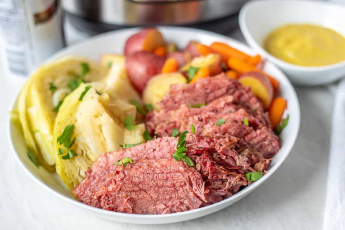 Instant Pot Dinner Ideas for Families Corned Beef, Cabbage, Potatoes and Carrots in white serving platter after being pressure cooked in Instant Pot.