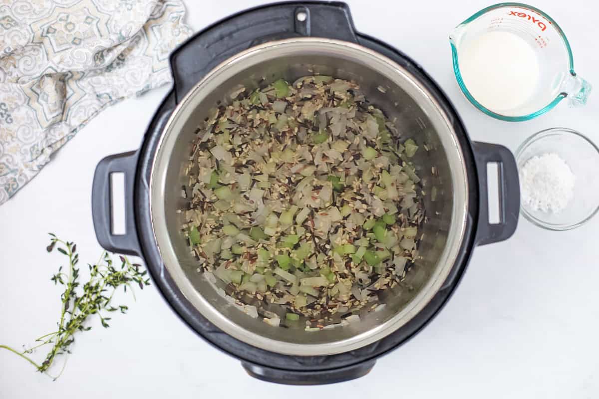 Easy Wild Rice Soup Recipe Onion, celery and wild rice sauteed inside inner pot to begin Instant Pot Wild Rice Soup.