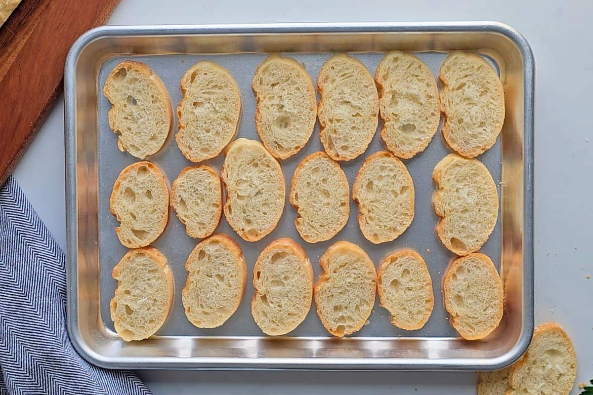 Recipe Pizza Dip Sliced baguette on baking tray after being lightly toasted to serve with pizza dip.