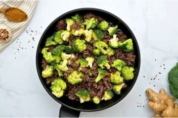 Browned beef in skillet with fresh broccoli florets and beef broth added in. pan