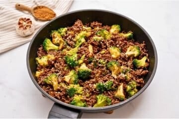 Sautéed ground beef with crisp tender broccoli tossed with sweet and savory sauce in sauté pan topped with sesame seeds.