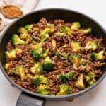 Ground beef with crisp tender broccoli tossed with sweet and savory sauce in saute pan topped with sesame seeds.
