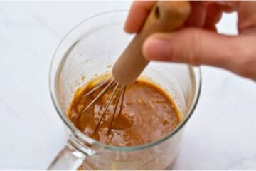 Small glass jar with sauce for beef and broccoli stir fry being whisked together.