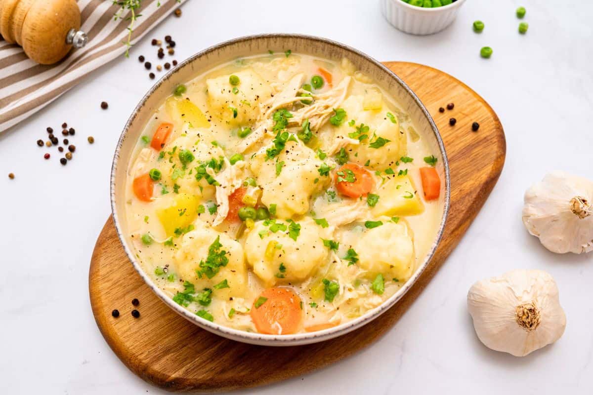 Soup Recipes for Winter Bowl of creamy chicken pot pie soup with shredded chicken, cooked carrots, potatoes, peas and homemade dumplings.