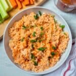 Shredded Instant Pot Buffalo Chicken in white dish next to carrots and celery