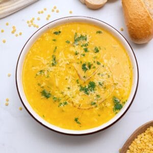 Bowl of Italian Pastina soup served with a drizzle of olive oil, fresh minced parsley, and parmesan cheese.