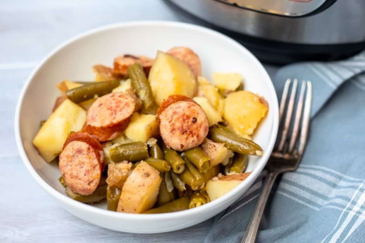 Easy Kid Friendly Instant Pot Dinner Recipes Sliced smoked sausage, red potatoes, and green beans cooked in Instant Pot and served in white bowl.