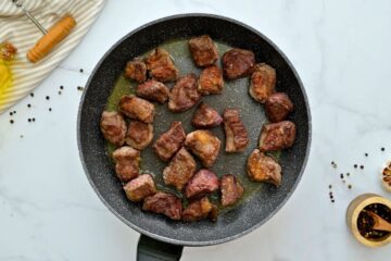 One inch chunks of beef coated in flour seared in a bit of oil in large skillet.