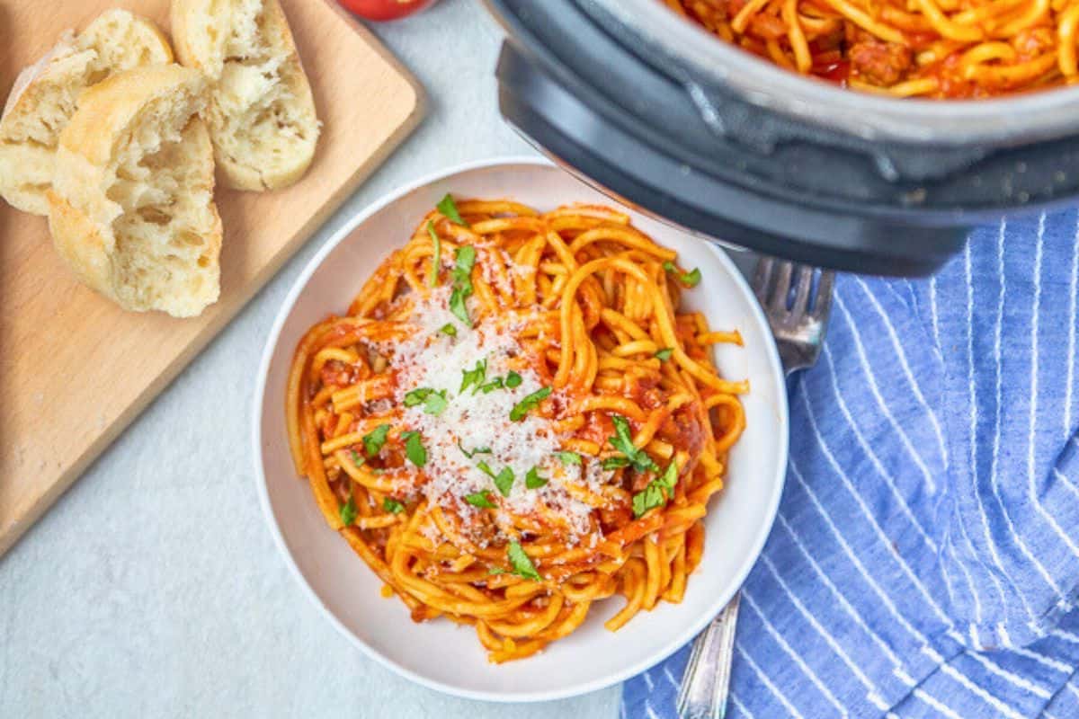 One Pan Family Dinners Perfectly cooked spaghetti with meat sauce in white bowl next to Instant Pot.