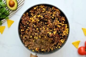 Ground beef, beans, and corn in large skillet seasoned with tomato sauce and taco seasoning to form base