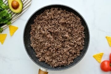 Cooked and crumbled ground beef in skillet for base of taco casserole.