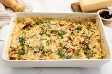 Baked orzo with sun-dried tomatoes and spinach in topped with basil and parmesan cheese.