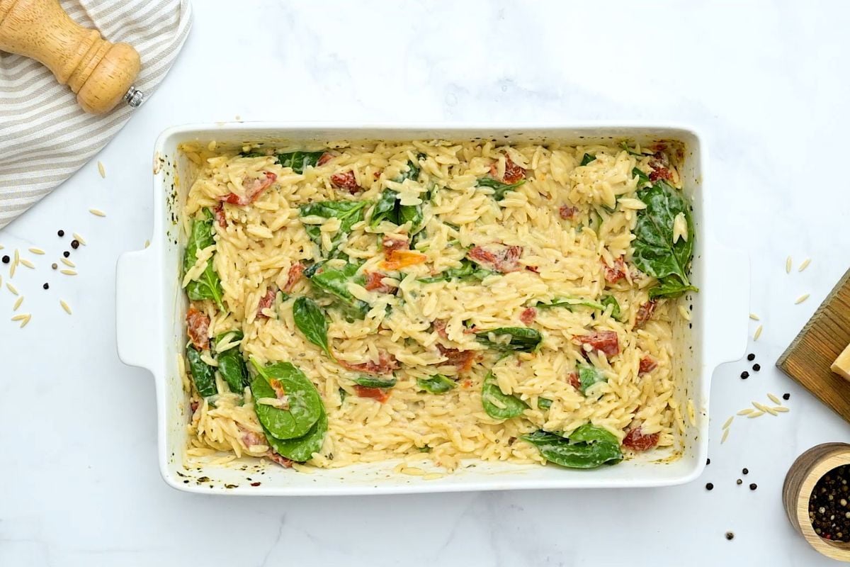 Baked Orzo with Sun-Dried Tomatoes Orzo in baking dish with spinach stirred into it.