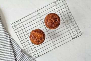 Two dog cakes made with oats and peanut butter on cooling rack cooling.