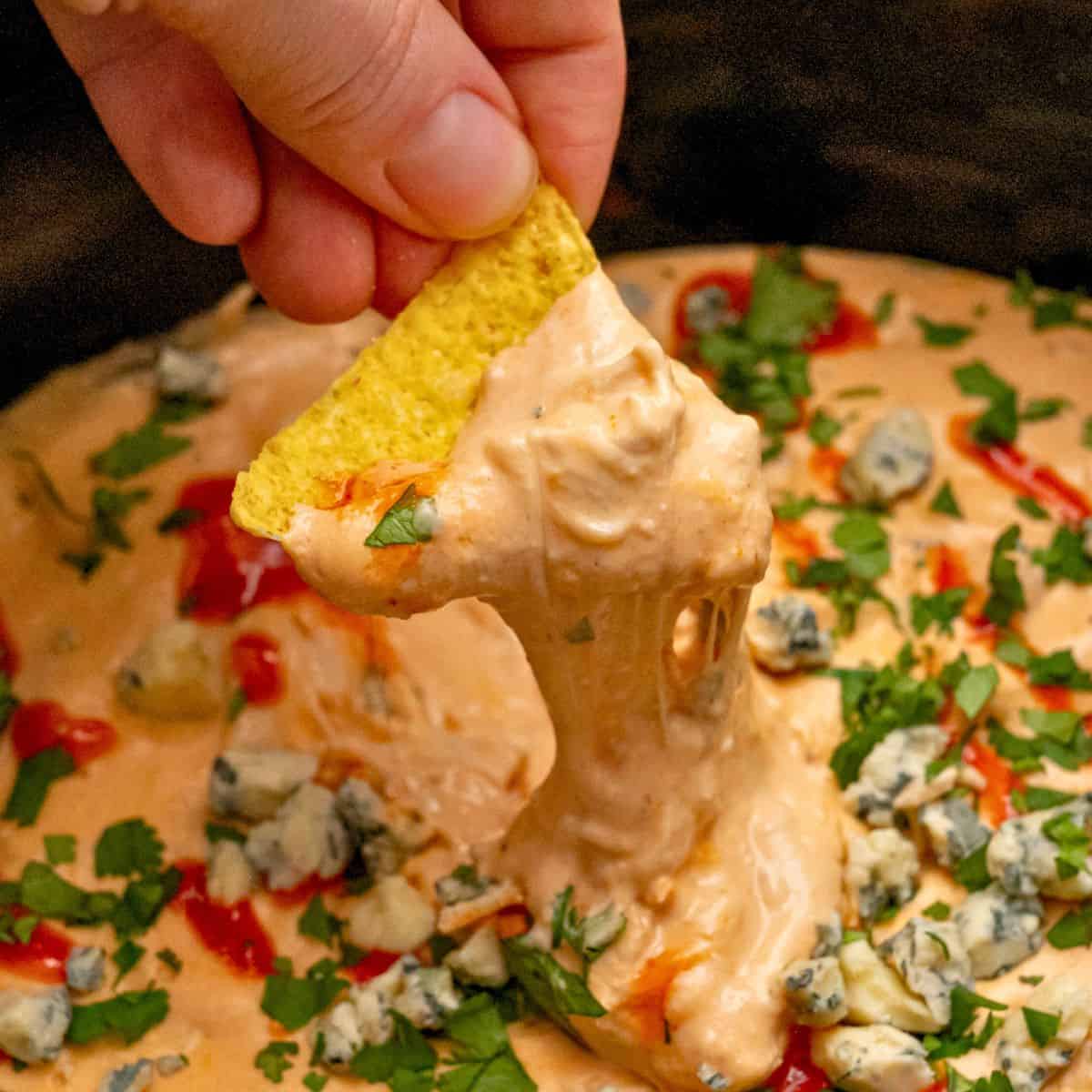 Easy Super Bowl Appetizers Tortilla chip scooping out buffalo chicken dip from crockpot.