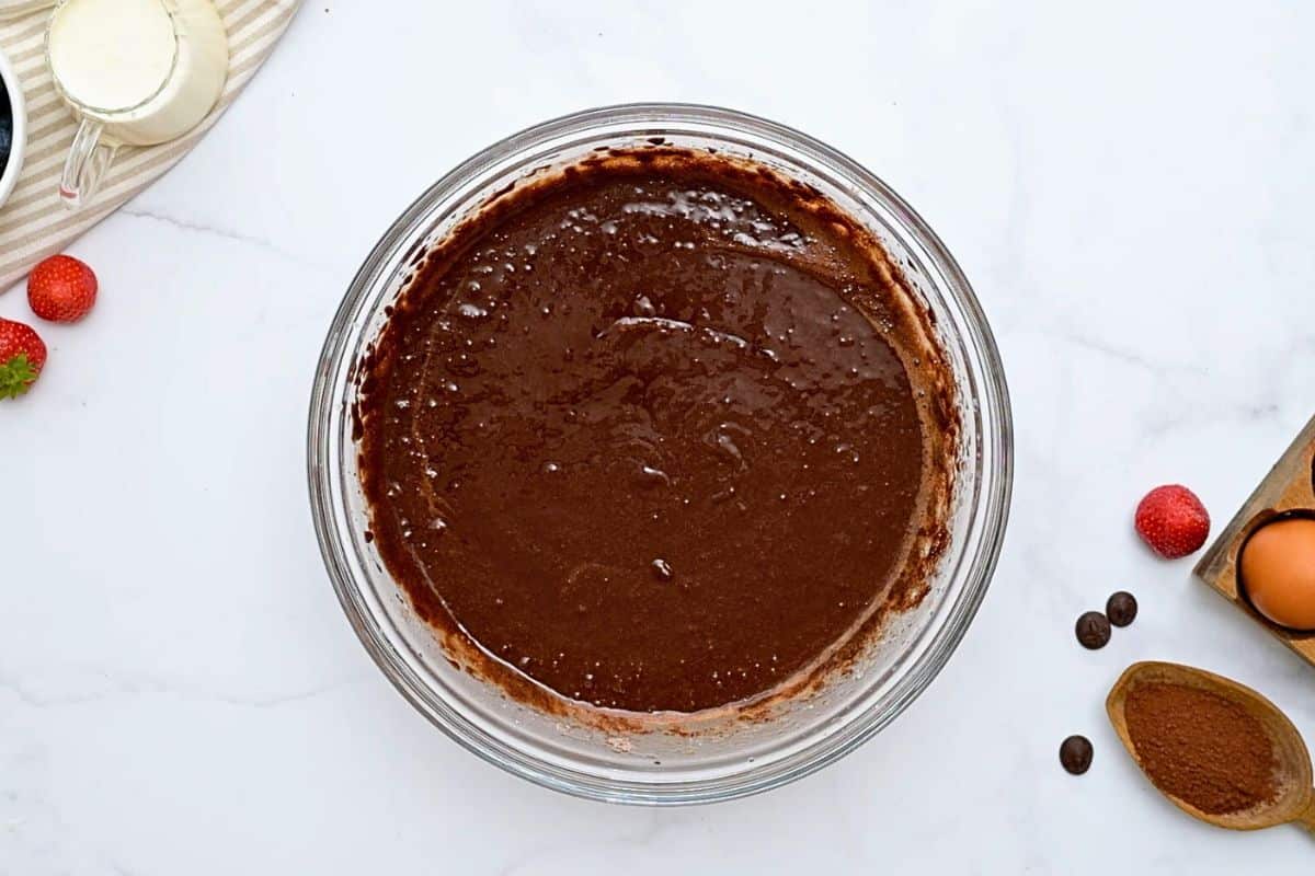 Chocolate Cake with Sour Cream Cake batter for chocolate bundt cake in mixing bowl with cocoa powder on the side.