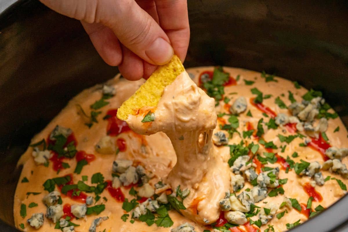 Crockpot Chicken Wing Dip Tortilla chip scooping out buffalo wing chicken dip from crockpot.