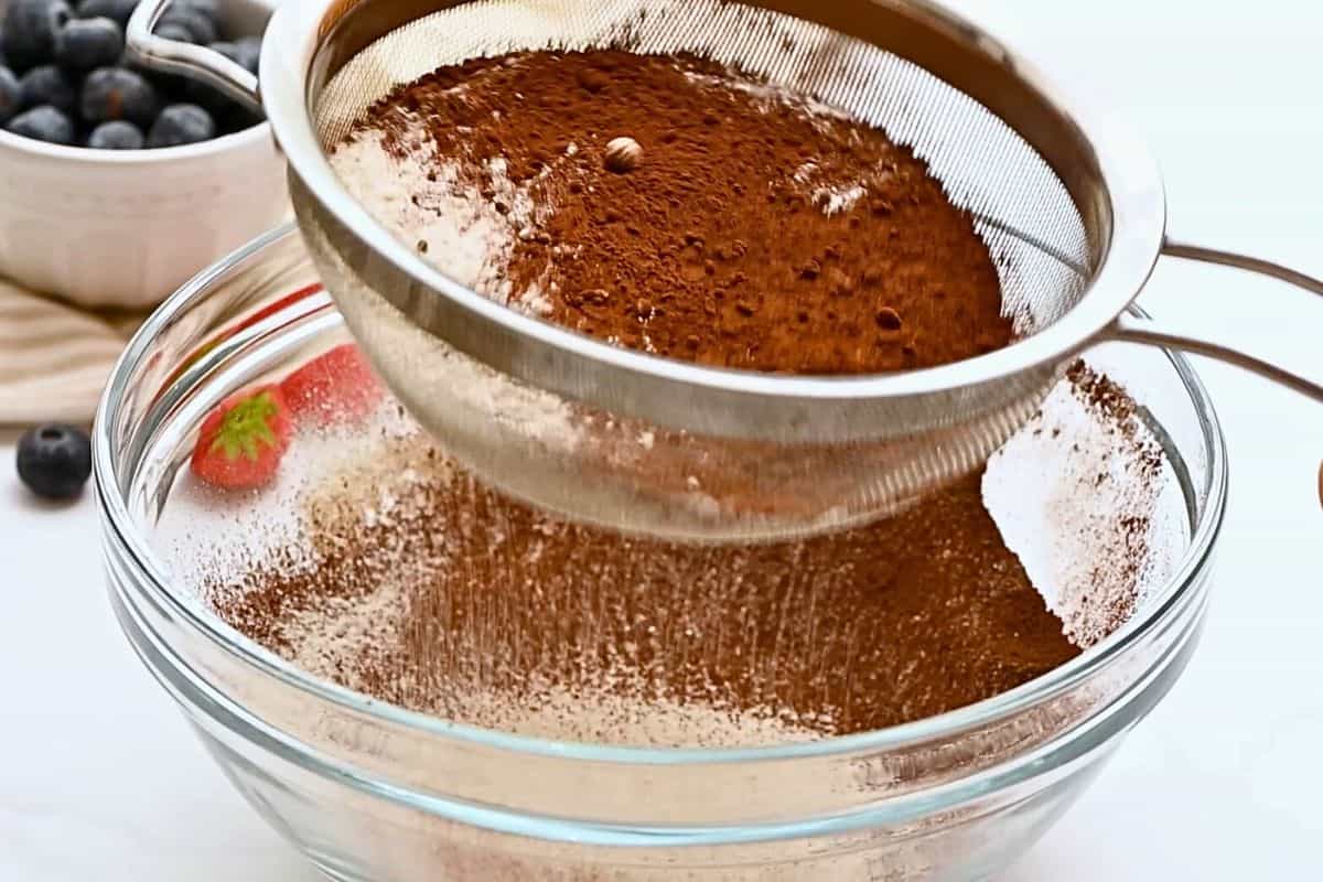 Chocolate Bundt Cake with Sour Cream Flour and cocoa powder being sifted into a large mixing bowl for chocolate bundt cake.